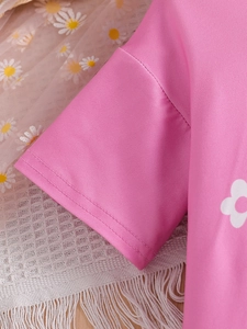 Close-up of pink girls top with daisy print and double-needle flat stitching details