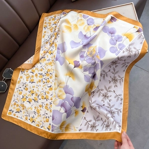 Floral satin square silk scarf in ginger yellow with eucalyptus leaf print on leather sofa