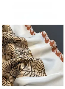 Dettaglio della trama satinata e del motivo a foglie vintage del foulard quadrato di seta