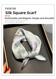 Gros plan d'un foulard en soie bleue avec imprimé floral mauve sur un plateau