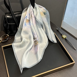 Carré en soie élégant bleu clair à motif floral posé sur un sac à main de luxe chic