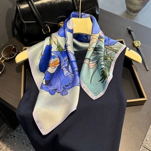 Elegant silk scarf with blue iris floral print styled on a beige hanger with accessories