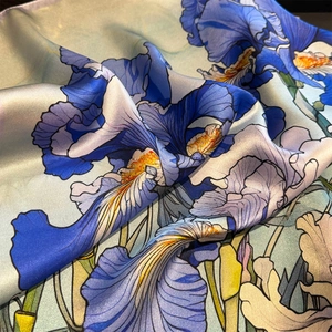 Macro shot of silk scarf showing vibrant iris floral prints and smooth satin texture