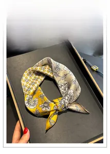 Détail d'un carré de soie imprimé à motifs floraux posé sur un plateau noir élégant
