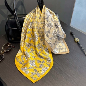 Foulard en soie à imprimé floral jaune et beige drapé sur un sac à main en cuir noir
