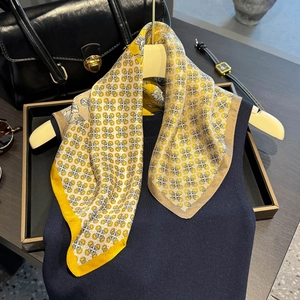 Carré de soie vintage jaune gingembre avec motifs géométriques sur un pull en maille