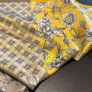 Détail d'un foulard en soie montrant une texture satinée et un motif floral à bord jaune