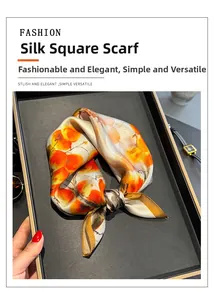 Detail view of a luxury silk square scarf with orange floral pattern in a gift tray