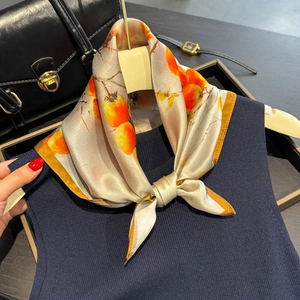 Elegant silk square scarf with persimmon print and orange border tied on a black handbag