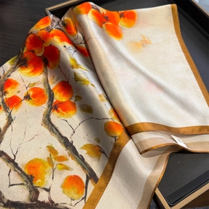 Detail of silk scarf showing vibrant red persimmon tree print and golden hemmed edges