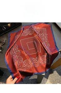 Detailed view of dark red paisley silk scarf draped over a black luxury handbag