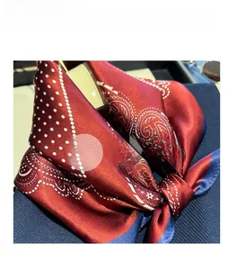 Macro shot of red paisley silk scarf showing soft texture and premium satin finish