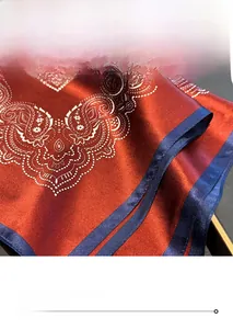 Detail of red paisley silk scarf with glossy satin finish and navy blue stitched edges