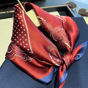 Elegant paisley silk scarf in dark red and navy blue tied on a stylish navy blue sweater