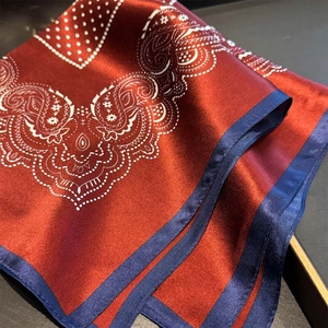 Detail of silk-texture square scarf featuring red paisley patterns and blue border