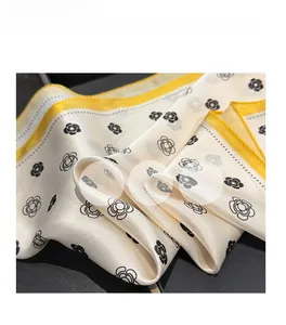 Detailed close-up of a silk scarf with camellia print and bright yellow edges