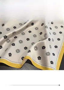 Macro detail of silk square scarf featuring camellia pattern and fine yellow stitched edges