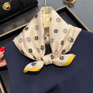 Silk square scarf with camellia print and yellow contrast border styled on a sweater