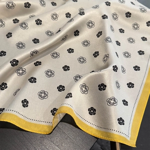 Detailed view of silk square scarf featuring camellia prints and yellow piped edges