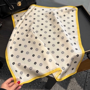 Close-up of silk square scarf featuring black camellia print and yellow borders
