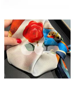 Detail of silk square scarf featuring vibrant red roses and soft, breathable texture