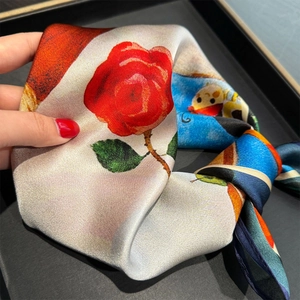 Detailed view of silk square scarf featuring artistic red roses and cartoon motifs