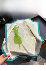 Detail of silk square scarf featuring green pineapple patterns on a display tray