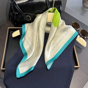 Elegant silk scarf with green borders and artistic print styled with a black leather bag