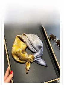 Detail of silk square scarf featuring yellow and grey paisley patterns with sunglasses