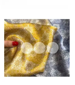 Close-up of silk scarf with bright yellow and grey-blue floral patterns and soft gloss