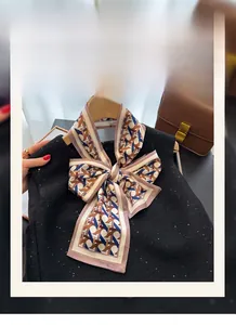 Detail of a geometric print silk-like scarf tied in a bow over a black sequin knit top