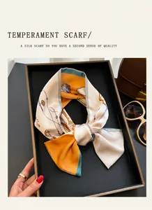 Detail of silk-like scarf with orange and cream patterns neatly folded on a black tray