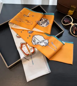 Detail of silk skinny scarf with orange fan pattern styled on a black display tray