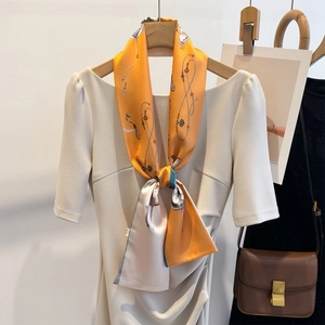 Silk-like long ribbon scarf with orange chain pattern styled on a dress collar