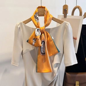 Elegant orange patterned long silk scarf tied on cream dress as stylish neck accessory