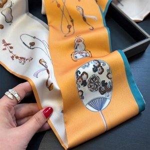 Detailed macro of a silk ribbon scarf with orange floral patterns and oriental motifs