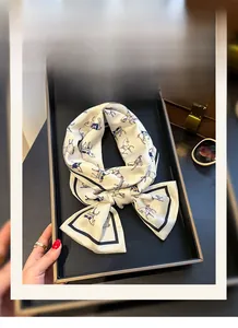 Detail of elegant horse print silk scarf tied in a bow on a black decorative tray