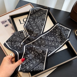 Detail view of black and white paisley skinny silk scarf tied as a luxury bag accessory
