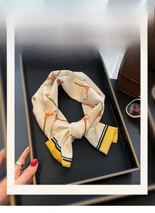 Detailansicht eines Seidenschals mit Blumenmuster auf schwarzem Tablett und Accessoires