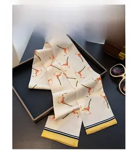 Detail eines Seidenschals mit orangefarbenem Call-Lilien-Druck in einem Tablett