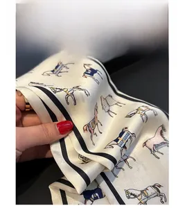 Close-up of dual-layer silk scarf featuring equestrian horse prints and elegant black borders