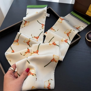 Detail eines eleganten Seidenschals in Elfenbein mit gelbem Calla-Lilien-Muster