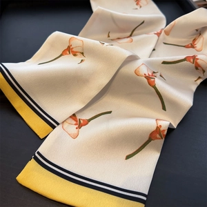 Nahaufnahme eines eleganten Satin-Schals mit Callas-Blumenmuster und gelbem Rand
