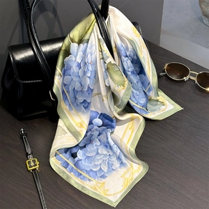 Elegant silk scarf with blue hydrangea pattern draped over a black leather briefcase