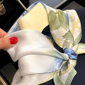 Close-up of silk square scarf with floral print and pearlescent texture on a bag