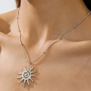 Détail du pendentif soleil argenté avec texture spirale sur chaîne serpent à perles