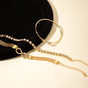 Parure de trois bracelets dorés avec symbole infini et cristaux sur velours noir