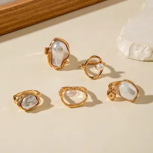 Macro detail of five vintage gold-plated rings with baroque pearls on white stone