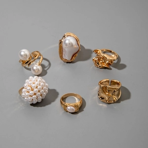Detailed set of six gold-plated alloy rings with baroque pearls on a grey background