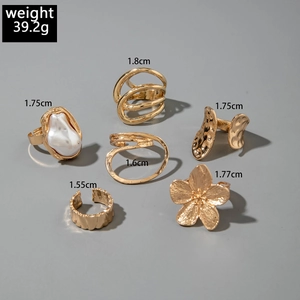Detailed view of 6-piece gold alloy ring set with baroque pearl and floral textures